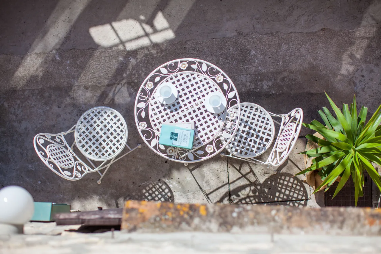 A white iron table and chairs from above, on stone, Nona Antonija apartment, Komiža