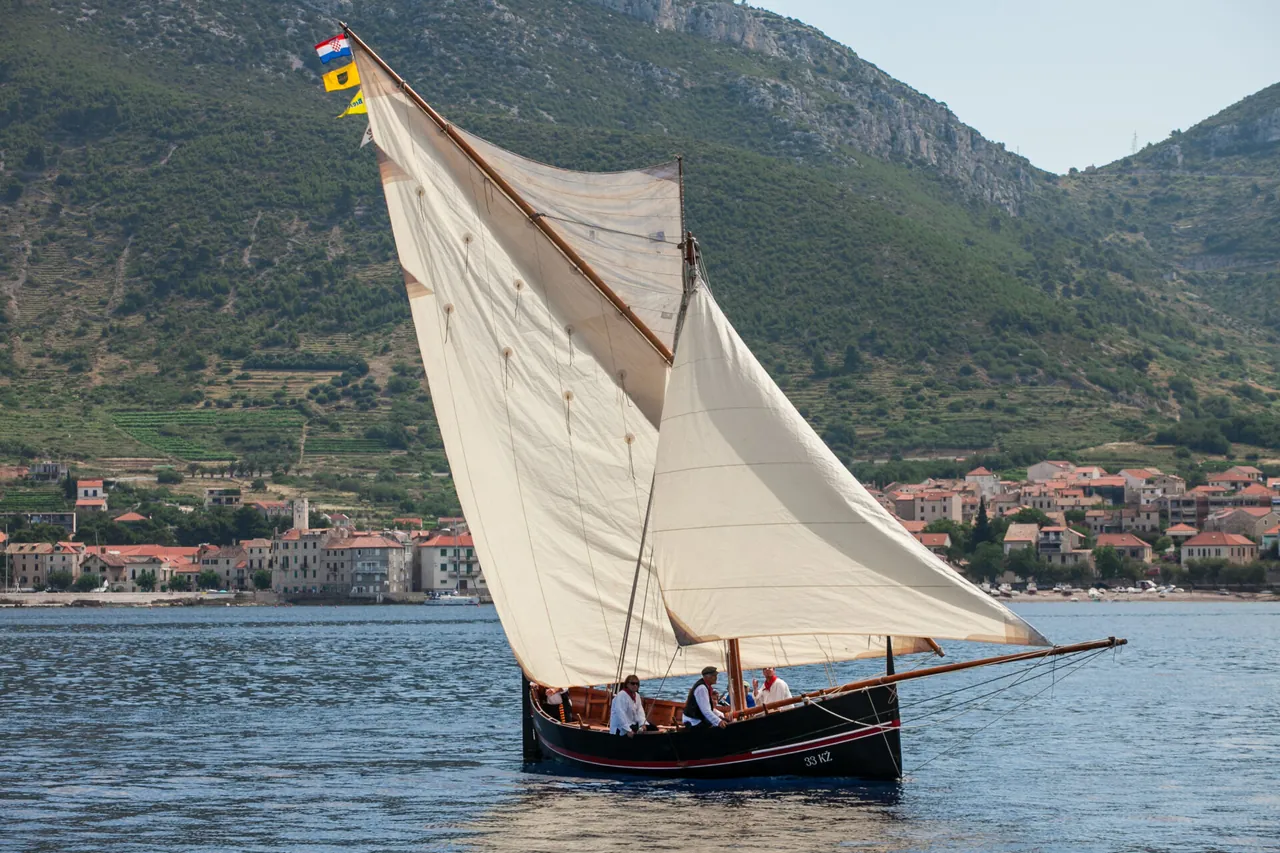 Una falkuša con la vela latina, dietro Comisa