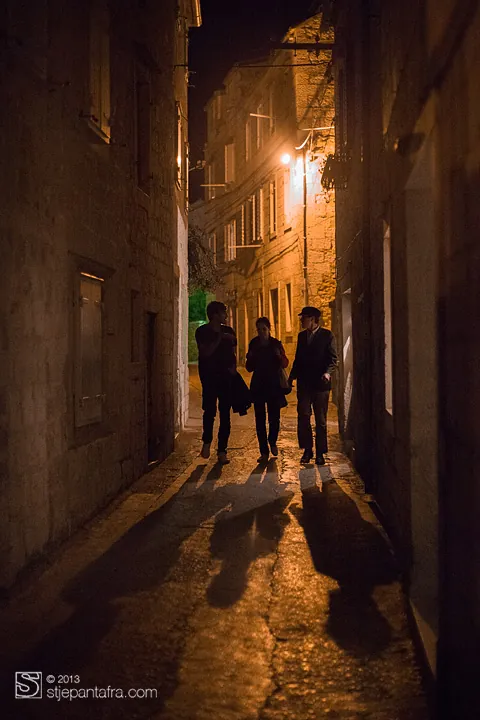 Un vicolo di pietra di notte, tre persone a passeggio