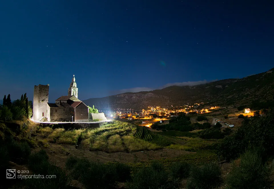 Notte: una chiesa e un campanile illuminati, le luci del paese